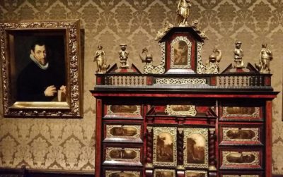 A portrait of a man next to a beautiful cabinet