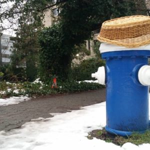 A blue fire hydrant with a straw hat on top of it