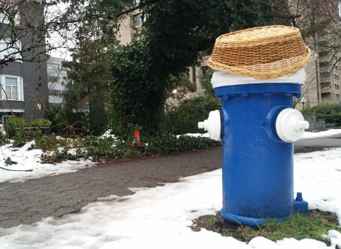 A blue fire hydrant with a straw hat on top of it
