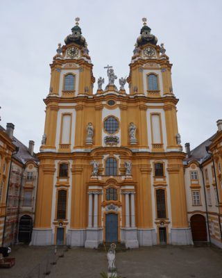 Front of the Melk Abbey church, an elaborately decorated building in orange and white