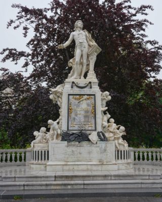 A marble statue of Mozart, with carved cherubs and musical instruments around the base