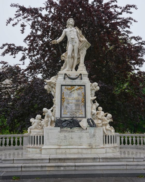 A marble statue of Mozart, with carved cherubs and musical instruments around the base