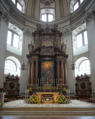 An altar with art and marble columns behind it