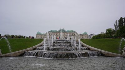 An elaborate fountain under a grey sky, with the Upper Belvedere Palace in the background