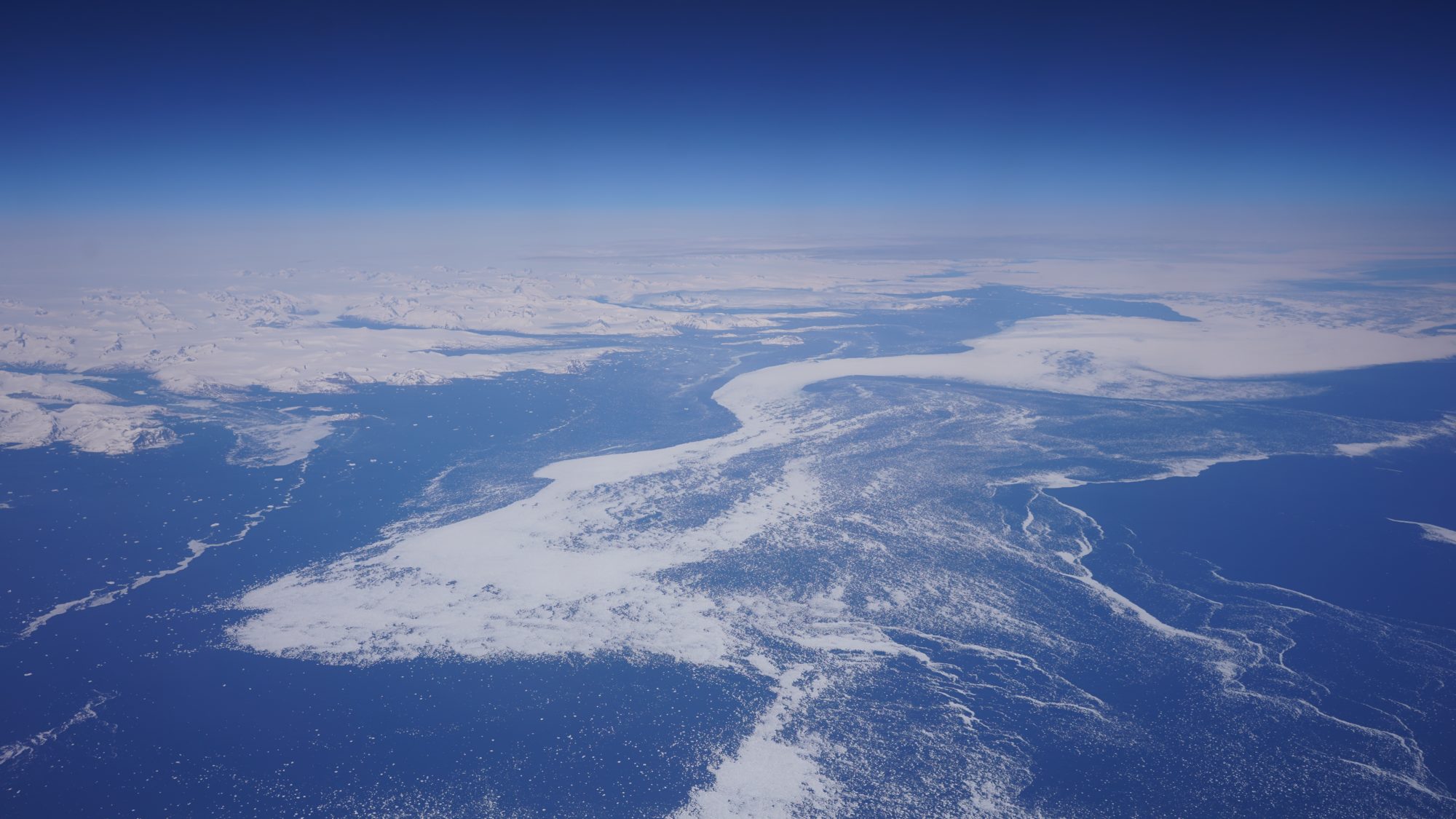 Off Grenland coast, a swirl of snow over dark blue ice. In the background we see actual snow-covered land