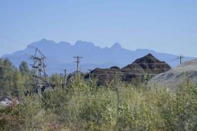 Big mounds of light material, maybe gravel, and darker material, maybe soil. In the background are mountains