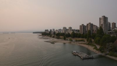 View of Sunset Beach and West End towers from Burrard Bridge. The sun is going down, and the sky is all orange / brown from the smoke