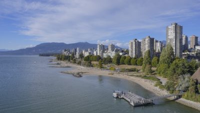 A view of the West End towers and Sunset Beach from Burrard Bridge. The sky is a nice blue, with some wispy clouds