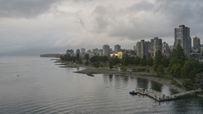 Sunset Beach and West End towers. The sky is grey, and one single building is reflecting gold light from the sunset