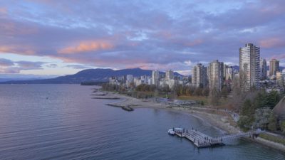 View of Sunset Beach and the West End from Burrard Bridge. The light clouds are coloured blue and orange-pink from the sunset, as are the towers
