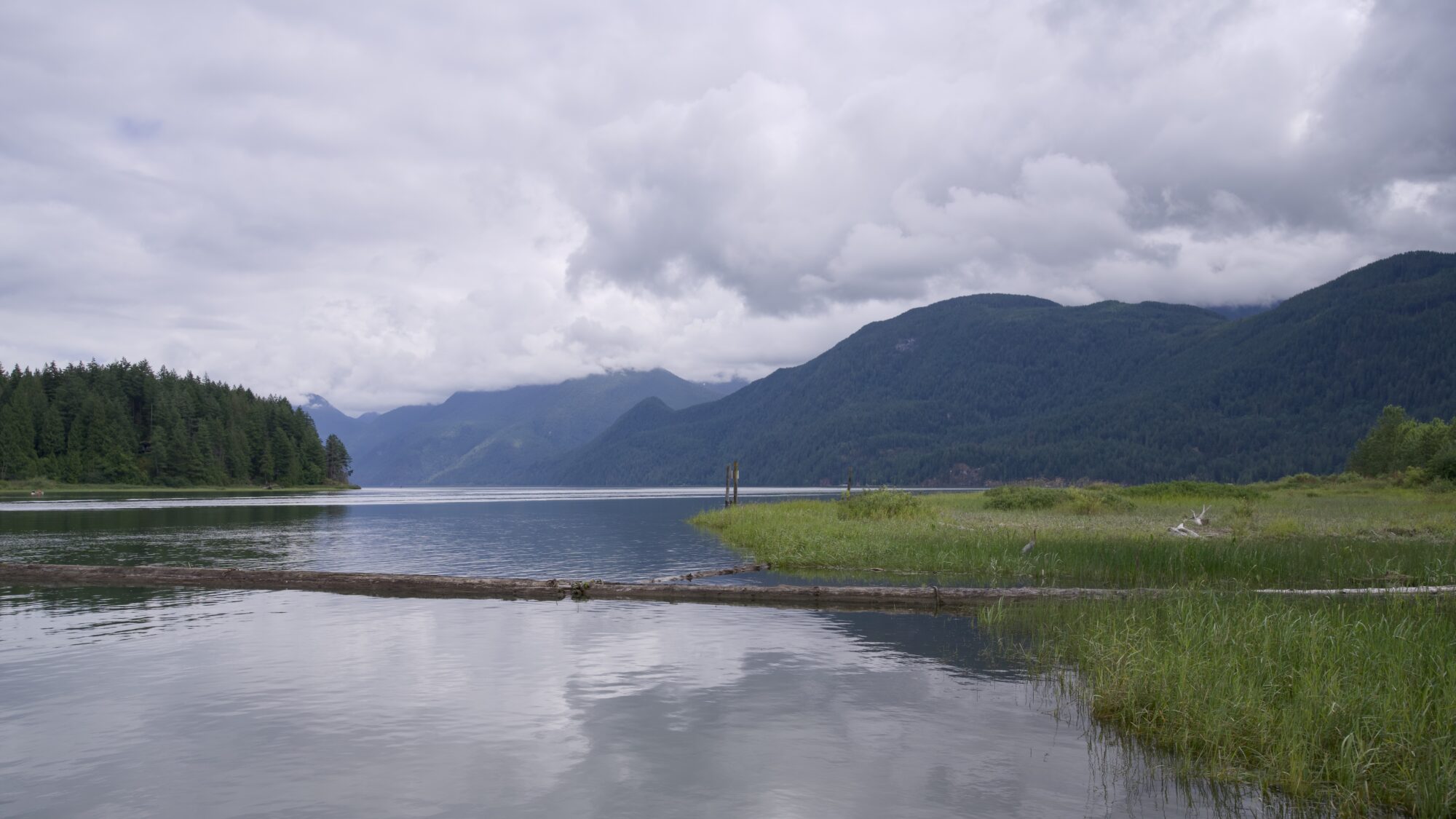 A lake nestled between mountains, under an overcast sky