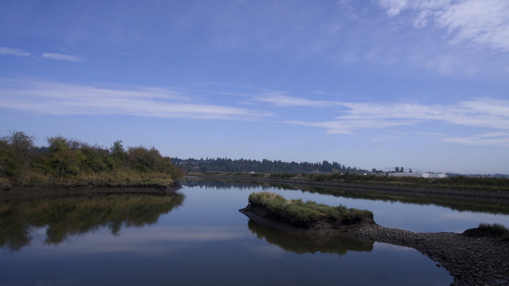 Serpentine River, shot from a little bay. The water is very still, and the sky is mostly blue